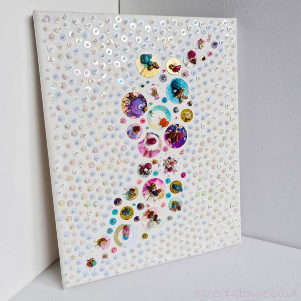 Abstract artwork featuring intricate hand-cut sequins, beads, and embroidery on canvas with a unique, multi-directional design.