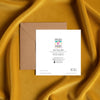 Square greeting card back with colorful logo and contact information placed on golden yellow satin fabric with a brown envelope