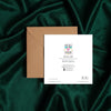 Square card back with colorful logo, artist name, and contact information placed on rich green satin fabric with a brown kraft envelope