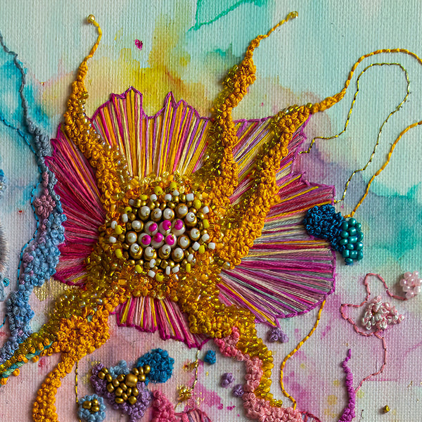 Close-up of colorful hand-stitched embroidery with beads and textured threads in an abstract floral design