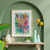 Framed Viola Five 2022 colorful abstract floral Giclée fine art print displayed on green wall above wooden table.