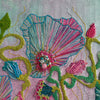 Close-up of hand-stitched embroidery with colorful threads, beads, and textured floral patterns on fabric background