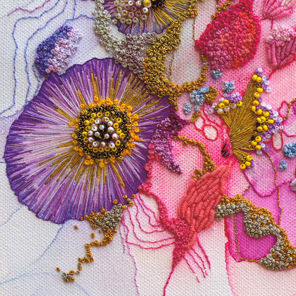 Close-up of hand-stitched Viola embroidery with intricate purple, pink, and gold thread details on fabric.