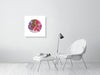 Minimalist modern living room with white chair and round colorful embroidery art print on white wall.
