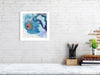 Framed Viola Seven 2023 Giclée fine art print showing detailed blue and purple embroidery on white wall above desk.