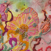 Close-up of colorful hand-stitched embroidery with intricate beads and threads on textured fabric background