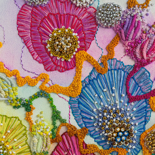 Close-up of colorful hand-stitched embroidery with beads and textured thread on a fine art print.