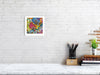 Viola Three 2022 detailed embroidery art print framed on white brick wall above minimalist desk setup