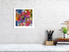 Framed Viola Two 2021 fine art print showing colorful abstract embroidery details on white wall above desk.