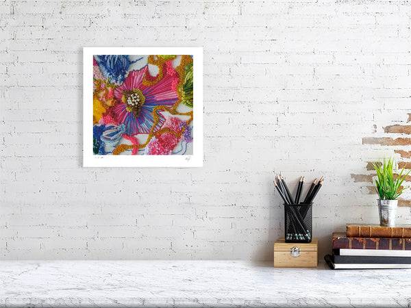Framed Viola Two 2021 fine art print showing colorful abstract embroidery details on white wall above desk.