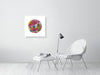 Minimalist room with white chair, ottoman, modern lamp, and colorful circular Viola Two 2021 embroidery art print on wall.