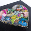 Close-up of a colorful embroidered heart artwork with beads and alcohol ink on black canvas.