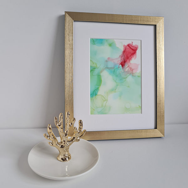 Abstract alcohol ink artwork Chloris Two 2018 in gold frame, mounted, with decorative gold coral ring holder on white surface