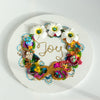 Abstract coral reef-inspired wreath with white flowers, beads, embroidery, and gold thread spelling "Joy" on round canvas