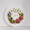 Abstract coral reef-inspired wreath with beads, flowers, embroidery, and the word "Joy" embroidered in gold thread.