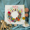 Abstract coral reef-inspired wreath artwork on square canvas with embroidery, beading, faux flowers, and gold metallic thread detailing
