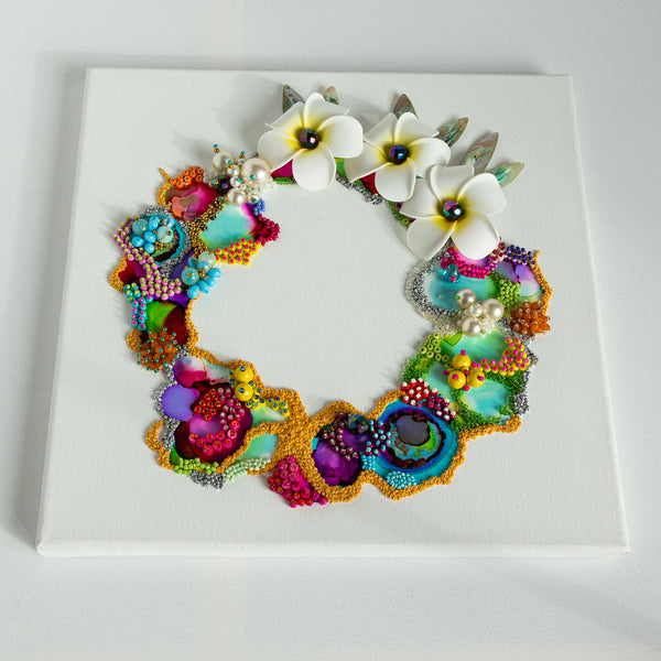 Abstract coral reef wreath artwork with vibrant colors, beads, embroidery, and white plumeria flowers on white canvas.
