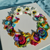 Abstract coral reef-inspired wreath with vibrant colors, beads, embroidery, faux flowers, and gold thread on white canvas background.