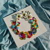 Abstract coral wreath artwork with vibrant colors, beads, faux flowers, and embroidery on white canvas background.