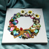 Abstract coral reef-inspired wreath artwork with beads, faux flowers, embroidery, and metallic threads on square canvas.