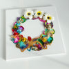 Abstract coral reef-inspired wreath artwork with plumeria flowers, beads, embroidery, and vibrant colors on square canvas.