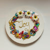 Abstract coral reef wreath with beads, faux flowers, embroidery spelling Joy on round white canvas