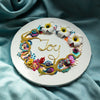 Coral Wreath Six 2022 with colorful beads, embroidery, faux flowers, and gold thread spelling "Joy" on round canvas.
