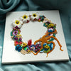Abstract coral reef wreath art with beads, embroidery, faux flowers, and mixed media on square canvas.
