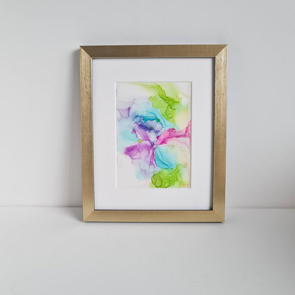 Abstract alcohol ink artwork titled Eostre 2018 with soft spring colors in gold frame on white wall background