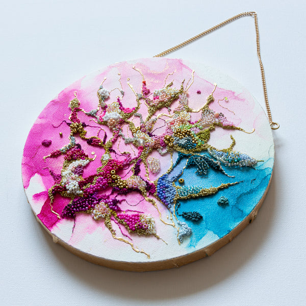 Round mixed-media artwork with alcohol ink, hand embroidery, seed beads, and gold leafed edges on canvas with hanging chain