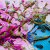 Close-up of intricate alcohol ink artwork with hand embroidery, seed beads, gold threads, and vibrant colors on canvas