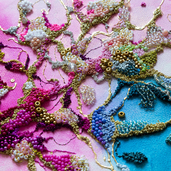 Close-up of intricate alcohol ink artwork with hand embroidery, seed beads, gold threads, and vibrant colors on canvas