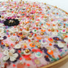Close-up of Flora 1.0 embroidery with lace flowers, colorful beads, sequins, and metallic threads on felt in a wooden hoop