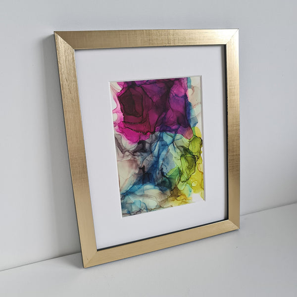 Abstract alcohol ink artwork "Hera, 2018" featuring vibrant purple, blue, green, and yellow hues in a gold frame.