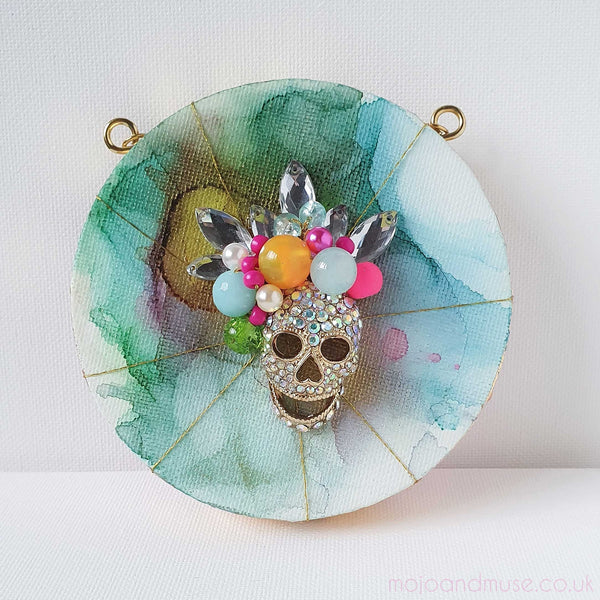 Features vibrant embroidery on canvas with beads, gold thread, and vintage jewelry, in a colorful abstract design inspired by the Day of the Dead.