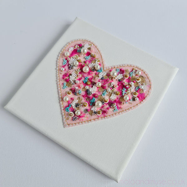 Canvas artwork featuring a heart embroidered with pearls, beads, metallic thread, and colorful alcohol ink accents.