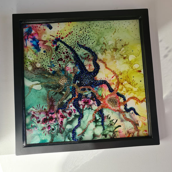 Colorful embroidered starfish and sea creatures in resin art with alcohol ink layers, framed in a wooden cradle for wall hanging.