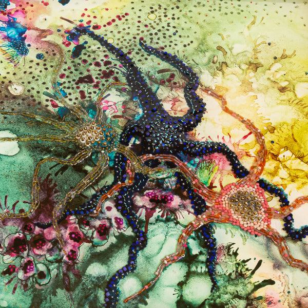 Close-up of colorful embroidered and beaded starfish set in resin with alcohol ink background on wooden cradle.