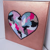 Hand-stitched heart artwork with beads and embroidery on metallic rose canvas, part of the 2021 Heart Series collection.