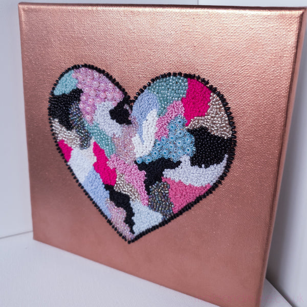 Hand-stitched heart artwork with beads and embroidery on metallic rose canvas, part of the 2021 Heart Series collection.