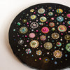 Round mixed-media artwork depicting colorful diatoms with beads and sequins on black canvas, titled Sea Jewels in the Snow Two.