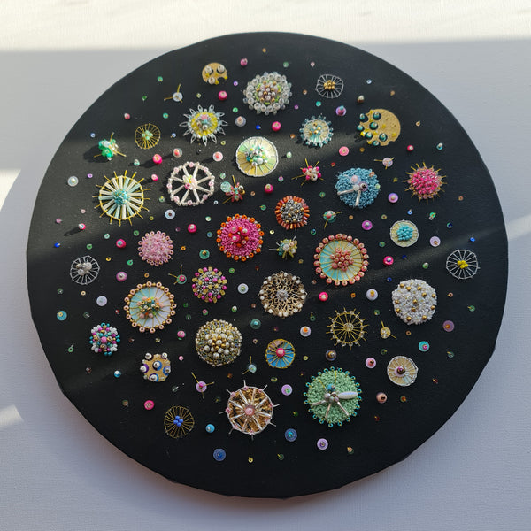 Circular mixed media artwork depicting colorful sea jewels and diatoms on a black canvas, 30cm diameter, ready to hang.