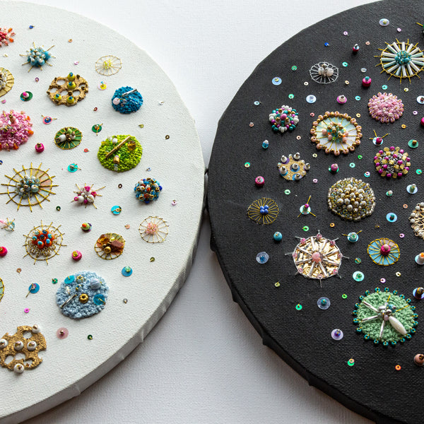 Two circular embroidered artworks with beads, sequins, and gold foil on black and white canvas, inspired by ocean diatoms.
