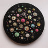 Circular mixed-media artwork depicting colorful diatom-inspired patterns on a black painted canvas background