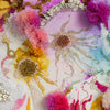 Close-up of colorful alcohol ink and hand-embroidered floral art with beads and gold threads on canvas