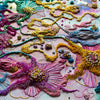 Close-up of Viola Five artwork with colorful embroidery floss, seed beads, gold thread, and abstract floral patterns on canvas.