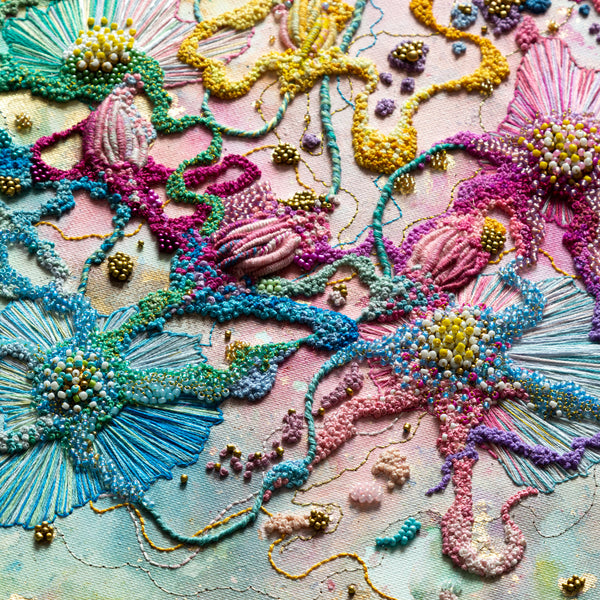 Close-up of vibrant embroidered flowers with seed beads and gold thread on canvas in abstract nature design