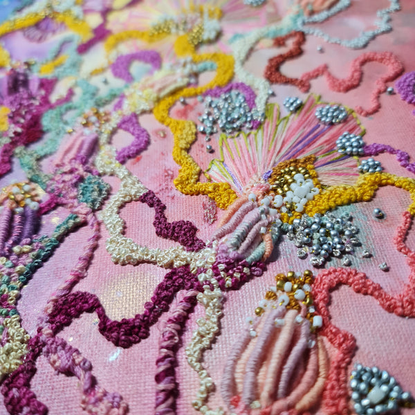 Close-up of Viola Six 2022 abstract embroidery with colorful threads, seed beads, and metallic accents on pink canvas.