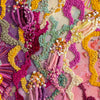 Close-up of abstract colorful embroidery with beads and metallic threads on canvas in vibrant organic shapes.