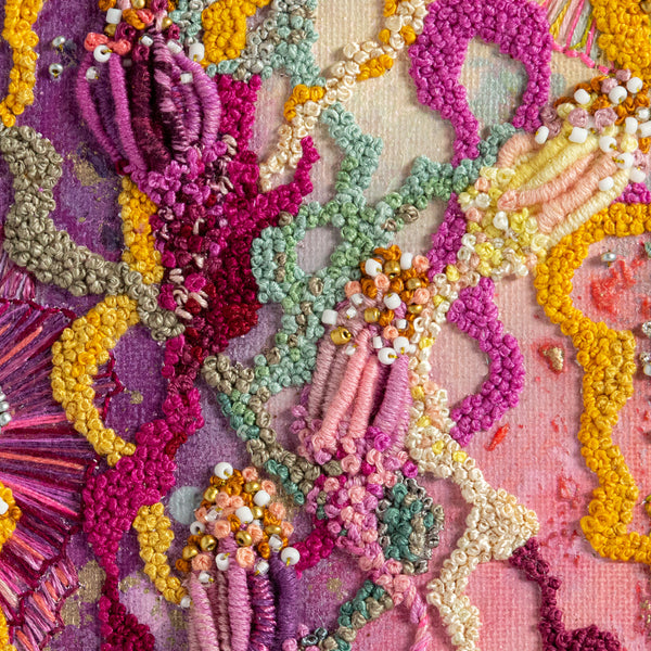 Close-up of abstract colorful embroidery with beads and metallic threads on canvas in vibrant organic shapes.